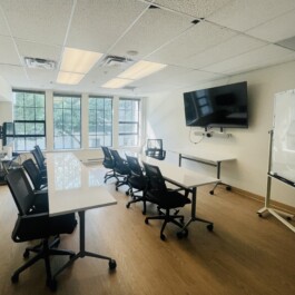 Bright board room with a large tv, whiteboard, cushioned office chairs, and large moving desks Vancouver Japanese Language School & Japanese Hall