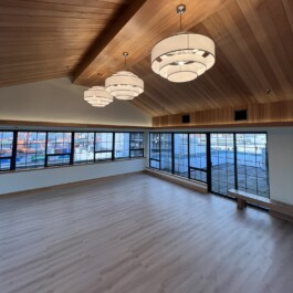 Spacious room with wooden ceiling and floor, artisanal ceiling lamps, white walls, and floor-to-ceiling windows Vancouver Japanese Language School & Japanese Hall