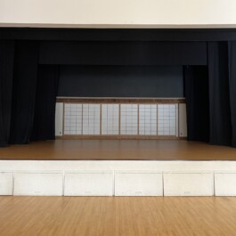 Gymnasium Stage with wooden flooring, black curtains, and sliding shoji wooden screen doors Vancouver Japanese Language School & Japanese Hall