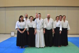 9 Aikido martial arts members standing on a green and blue mat. Vancouver Japanese Language School & Japanese Hall